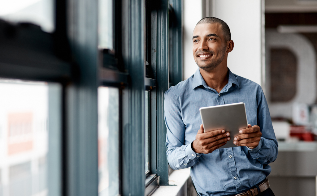 Shot of a young businessman using a digital tablet while standing at a window in an office There's lots to gain through smart apps
